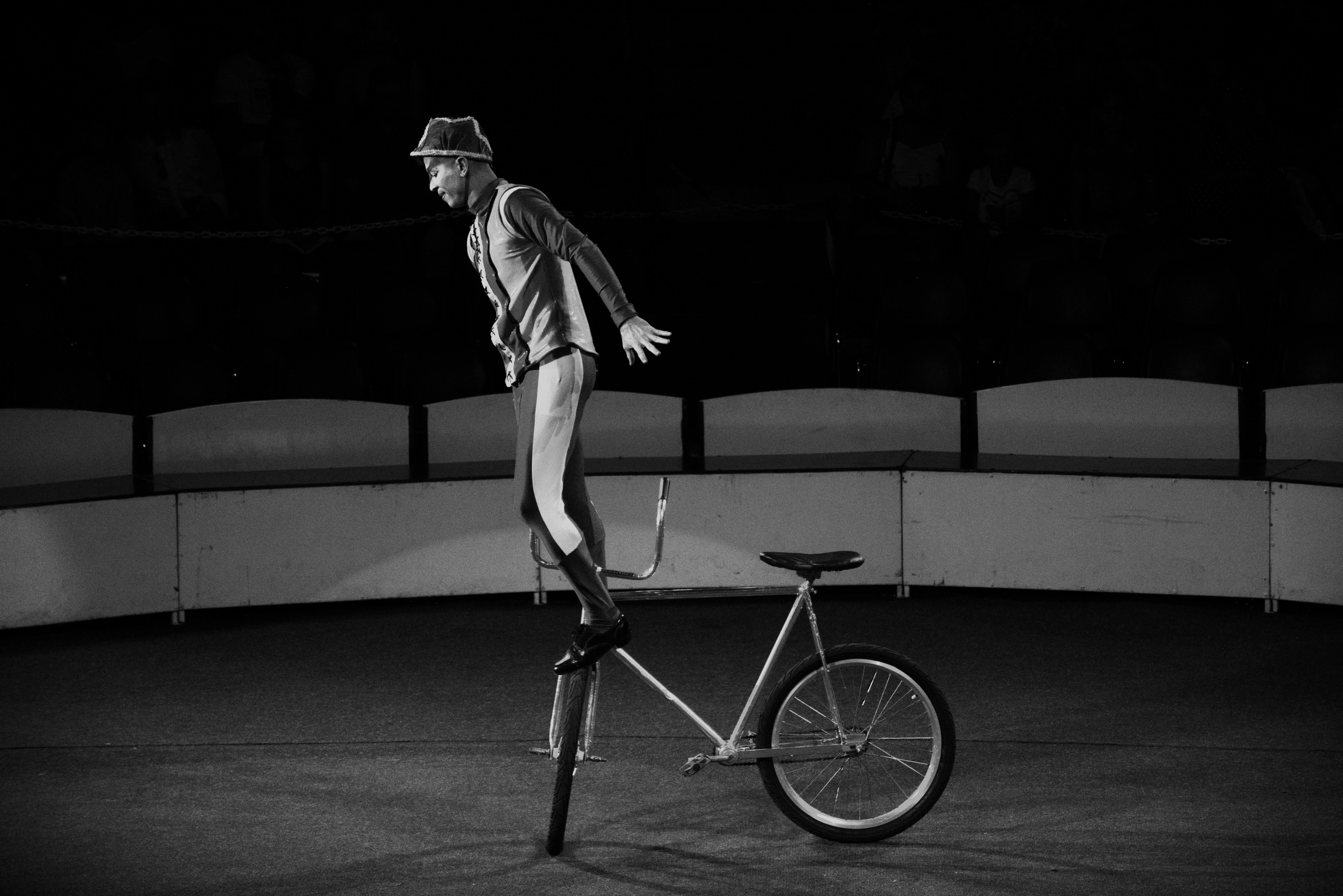 Performer standing on bicycle pedals, arms extended for balance