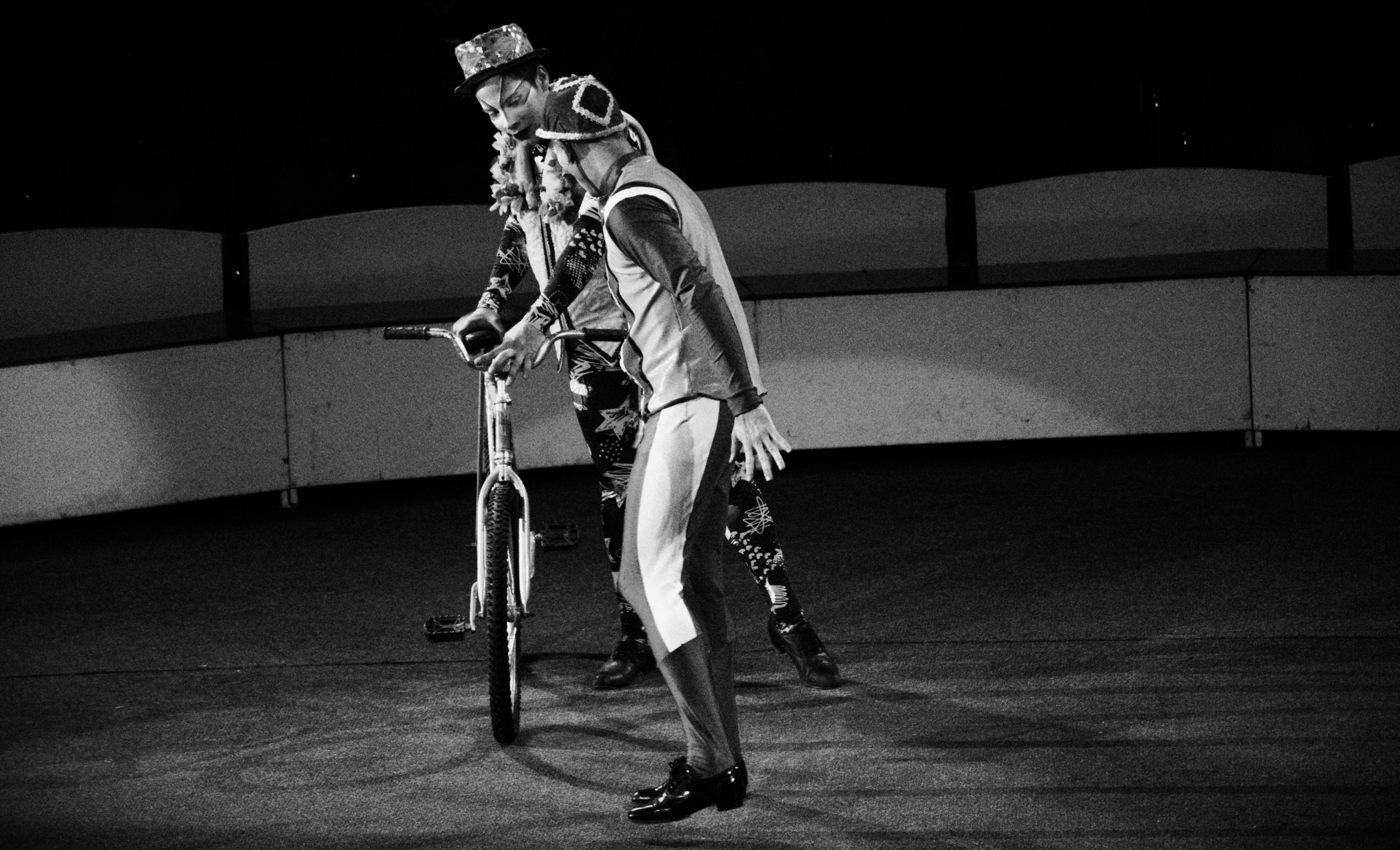 Two performers with a bicycle on the circus floor