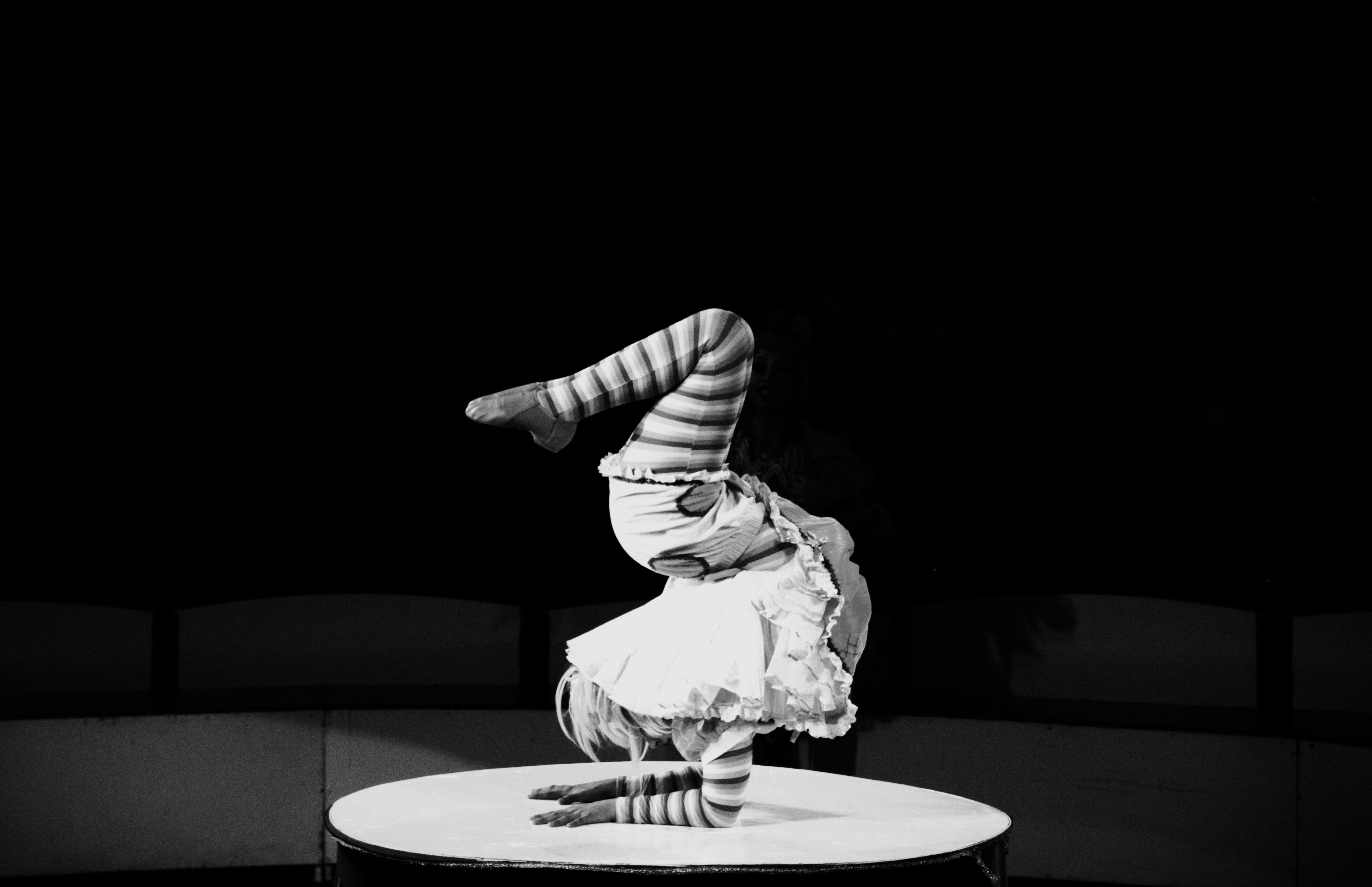Contortionist in handstand on table, striped tights
