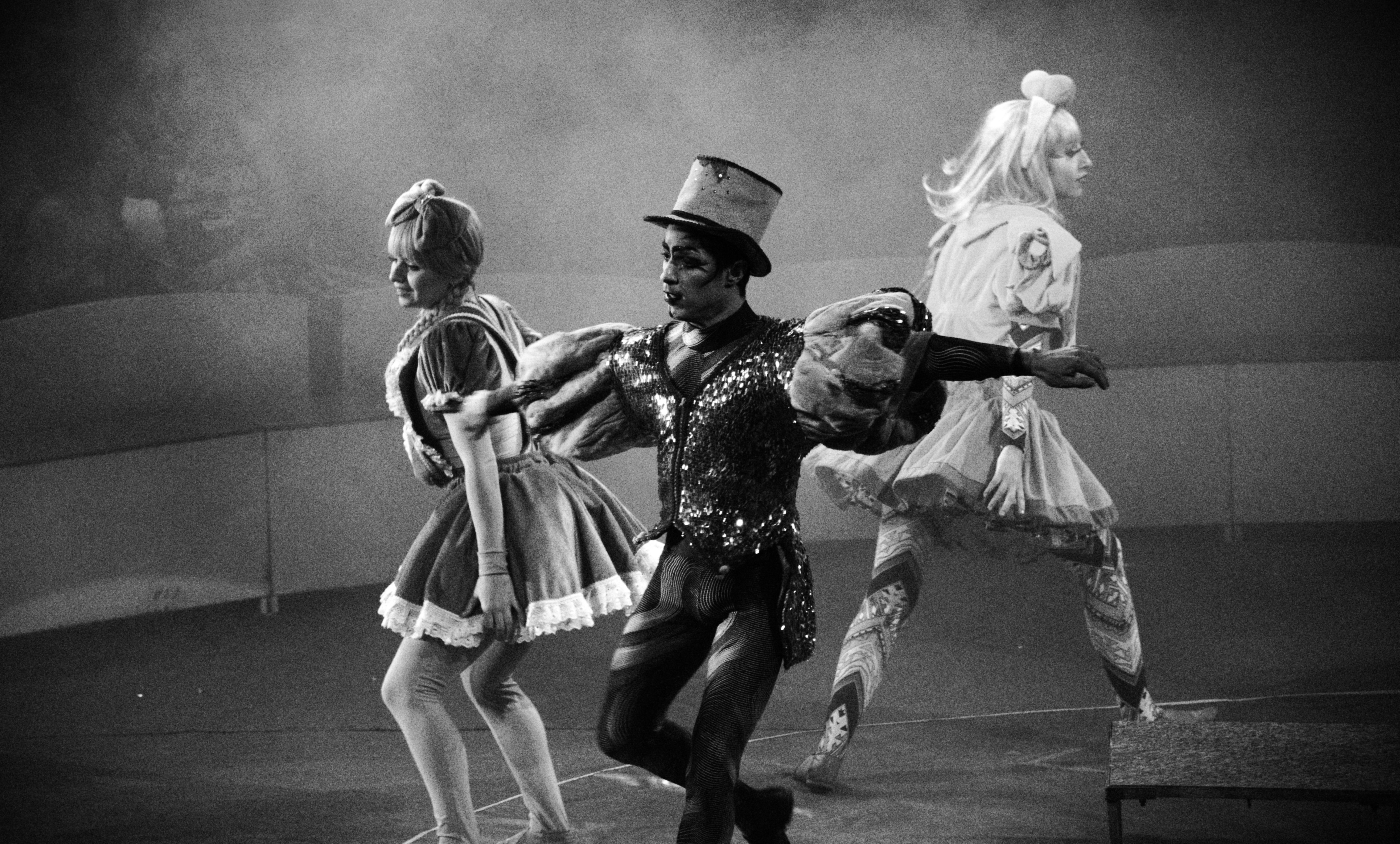 Performers striding across the ring in sequined costumes amid stage smoke
