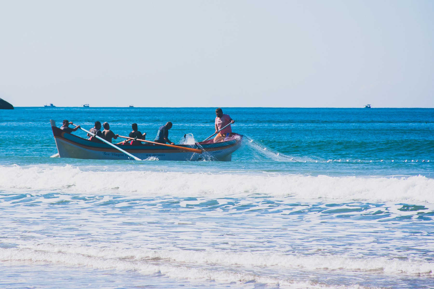 Fishermen launching a rowing boat through surf